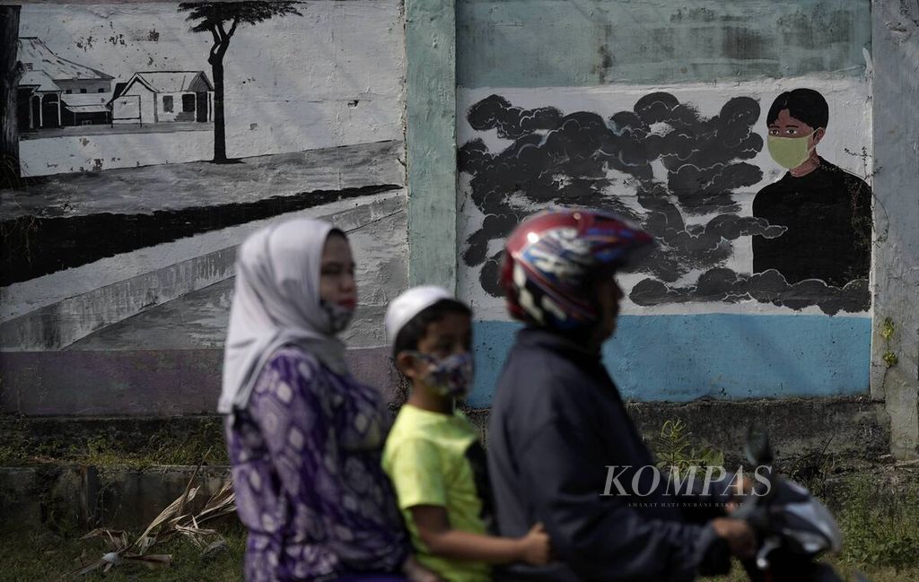 Warga melintas di depan mural bergambar orang memakai masker di Tebet, Jakarta Selatan, Jumat (24/7/2020). Kesadaran mematuhi protokol kesehatan terus disuarakan, di antaranya, melalui mural untuk pencegahan penyebaran Covid-19.