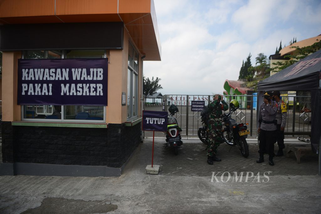 Personel polisi dan tentara berjaga di pintu masuk obyek wisata Ketep Pass, Sawangan, Kabupaten Magelang, Jawa Tengah, yang ditutup sementara, Selasa (11/5/2021). 