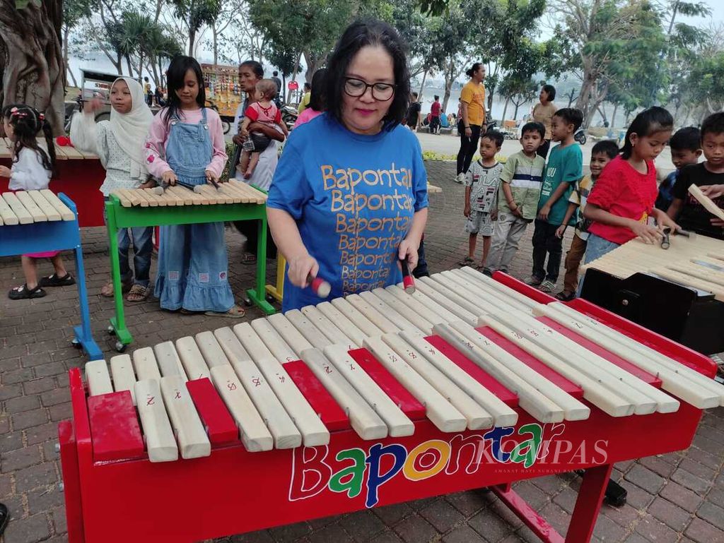 Beiby Sumanti mendampingi anak-anak yang belajar bermain kolintang di Waduk Pluit, Jakarta, Minggu (10/9/2023).