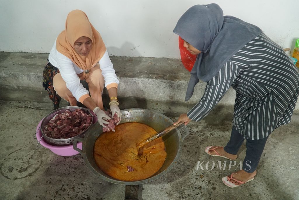 Ibu-ibu anggota Dharma Wanita BPBD Provinsi Sumatera Barat memasukkan daging ke kalio dalam membuat rendang untuk dikirimkan kepada korban gempa M 6,5 Cianjur di belakang kantor BPBD Sumbar, Padang, Sumbar, Rabu (23/11/2022). 