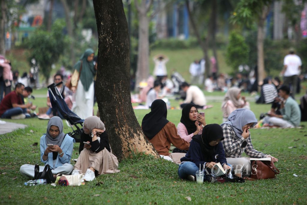 Warga bercakap-cakap sambil menikmati suasana sore di Hutan Kota Gelora Bung Karno, Jakarta, Minggu (25/6/2023).