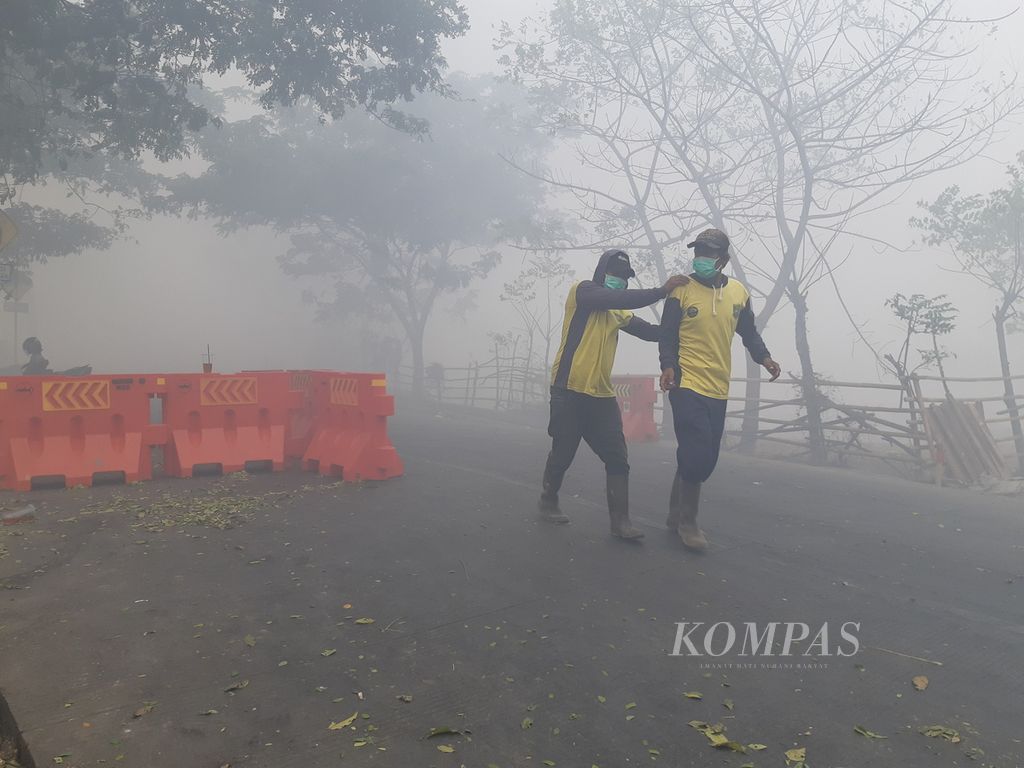 Dua petugas sedang berada di kabut asap dampak dari Kebakaran TPA Rawa Kucing, Kecamatan Neglasari, Kota Tangerang, Senin (23/10/2023). Sampai saat ini upaya pemadaman terus dilakukan agar asap tidak mengganggu aktivitas warga.