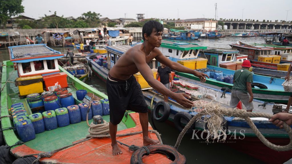 Nelayan melemparkan tali dari kapal motor nelayan yang akan bersandar di tanggul pengaman pantai di Pelabuhan Lama Kalibaru, Cilincing, Jakarta Utara, Jumat (21/7/2023).