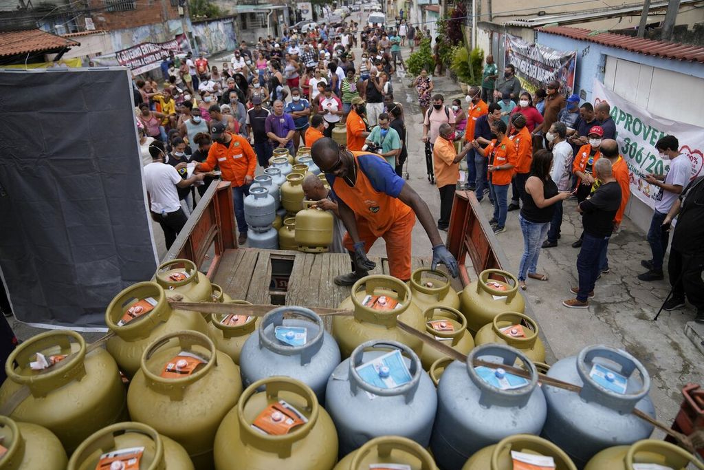 Pekerja menurunkan tabung gas memasak dari truk pengangkut di favela (permukiman) Vila Vintem di Rio de Janeiro, Brasil, Oktober 2021.