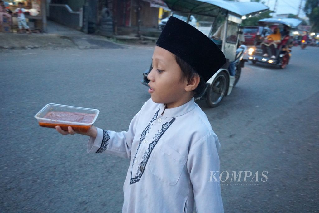 Seorang anak berjalan membawa makanan untuk berbuka puasa di Jalan Soeprapto, Gogagoman, Kotamobagu, Sulawesi Utara, pada Selasa (4/5/2021) sore.