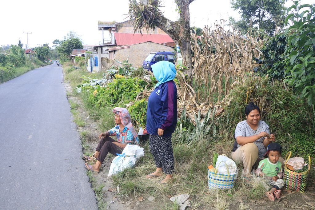 Para petani menunggu angkutan saat hendak pulang dari ladang di Desa Gamber, Kecamatan Simpang Empat, Kabupaten Karo, Sumatera Utara, Kamis (11/5/2023). Aktivitas pertanian di sekitar Gunung Sinabung menggeliat setelah dua tahun tidak ada erupsi.