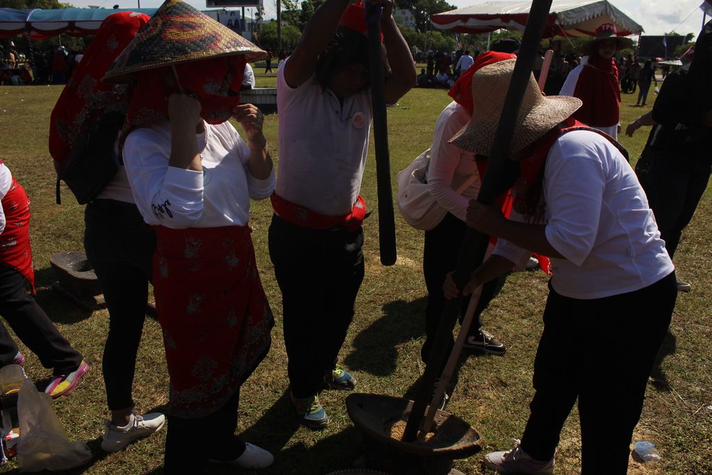 Peserta acara mangenta atau membuat kue beras ketan, dalam rangkaian acara Festival Budaya Isen Mulang (FBIM) 2022 di Palangkaraya, sedang menumbuk padi ketan yang sudah disangrai di tungku api sebelumnya, pada Minggu (22/5/2022).
