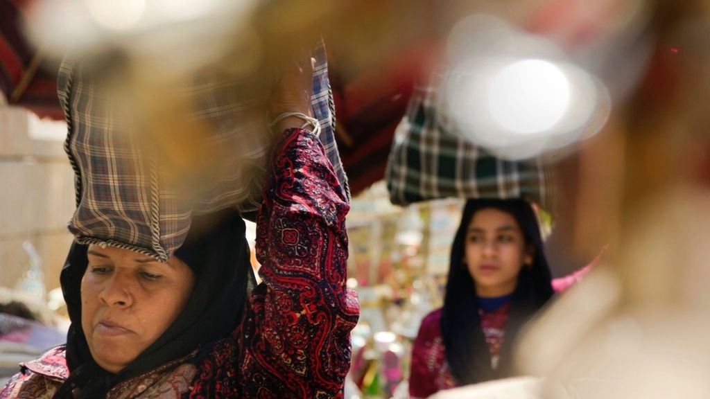 Para perempuan, di Kairo, Mesir, Senin (15/5/2017), membawa barang belanjaan mereka di pasar lampu Ramadhan yang terkenal, dalam rangka persiapan bulan puasa.