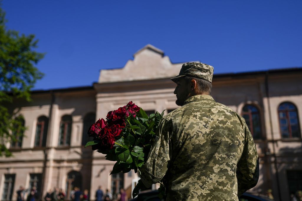 Tentara Ukraina memegang bunga saat pemakanan di Zhytomyr, Ukraina, 3 Juni 2022.
