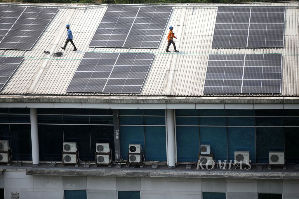 Pekerja berada di atap bangunan yang penuh dengan panel surya di Kampus Universitas Multimedia Nusantara, Kabupaten Tangerang, Banten, 20 September 2023.