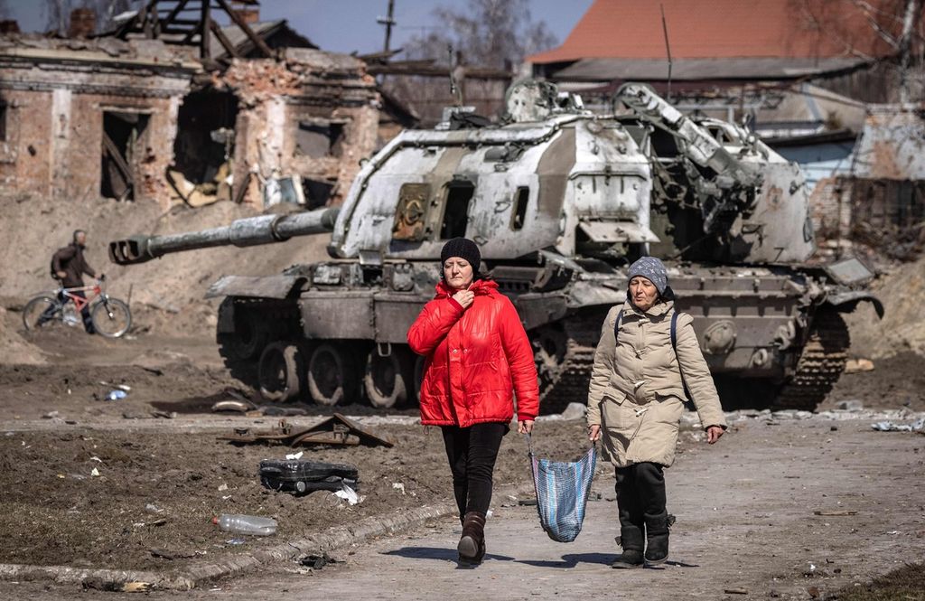 Warga berjalan melewati tank Rusia di kota Trostianets, Ukraina, 29 Maret 2022. 