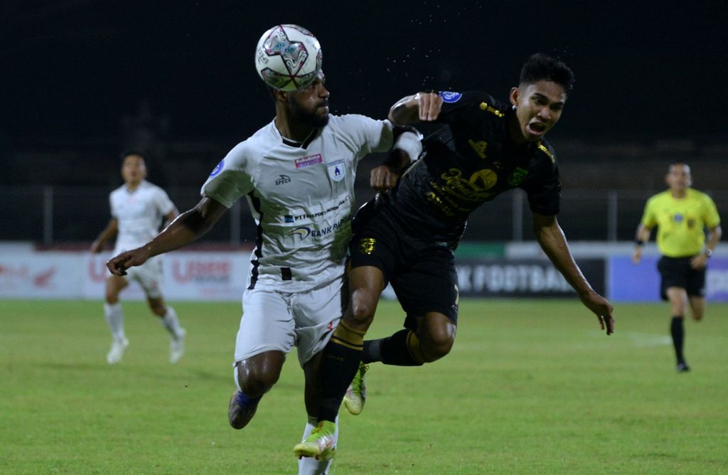 Pemain Persipura Jayapura, Donni Harold Monim (kiri), berebut bola dengan pemain Persebaya Surabaya, Marselino Ferdinan (kanan), pada laga Liga 1 Indonesia di Stadion I Gusti Ngurah Rai, Denpasar, Bali, Minggu (6/2/2022). 