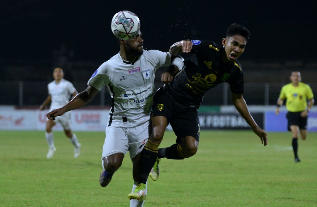 Pemain Persipura Jayapura, Donni Harold Monim (kiri), berebut bola dengan pemain Persebaya Surabaya, Marselino Ferdinan, pada laga Liga 1 Indonesia di Stadion I Gusti Ngurah Rai, Denpasar, Bali, Minggu (6/2/2022). Persipura menang 2-0.