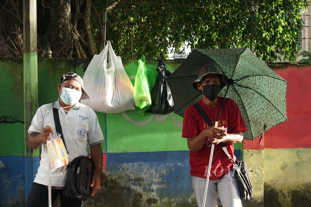 Simon Pare (47, kiri) bercanda dengan Latif Toisi (47), pertengahan April 2022, selagi berjualan tisu dan kacang di Jalan Sam Ratulangi 3, Wenang Utara, Manado, Sulawesi Utara. 