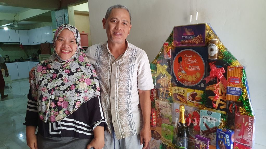 Ibu Dijah dan suaminya berfoto di depan parsel yang baru selesai mereka rangkai dan siap untuk dijual di Pasar Cikini, Jakarta Pusat, Selasa (26/3/2024).