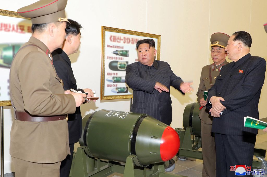 Dalam foto yang direkam pada 27 Maret 2023 ini terlihat pemimpin Korea Utara Kim Jong Un (tengah)  memeriksa hulu ledak nuklir di lokasi yang tidak disebutkan. 