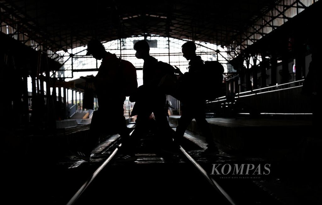 Penumpang kereta api menyeberangi rel menuju gerbong yang baru tiba di Stasiun Poncol, Kota Semarang, Jawa Tengah, Senin (1/5/2023). Selama libur panjang Lebaran ini, kereta api menjadi salah satu transportasi utama bagi pemudik menuju sejumlah wilayah di Jawa.