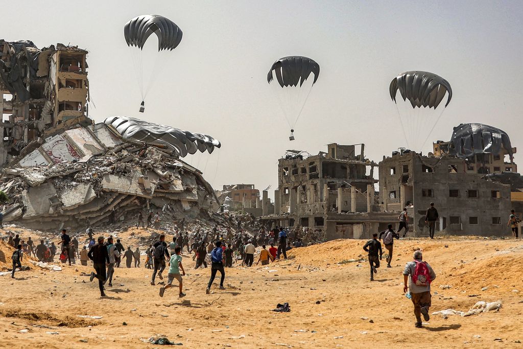Warga Gaza berlarian menuju bantuan kemanusian yang dijatuhkan dari udara di wilayah udara Gaza, Selasa (23/4/2024).