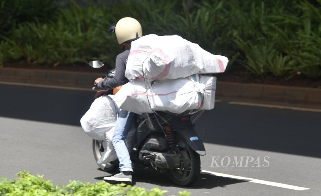 Kurir membawa barang menggunakan sepeda motor di kawasan Setiabudi, Jakarta Selatan, Selasa (9/11/2021). Penggunaan jasa kurir oleh masyarakat meningkat di masa pandemi ini terutama untuk mengirimkan barang yang dibeli dari lokapasar. 