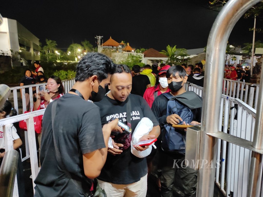 Petugas tiket memindai <i>barcode </i>tiket digital pendukung Bali United sebelum memasuki pintu masuk Stadion Kapten I Wayan Dipta pada laga Bali United kontra Kedah Darul Aman dalam penyisihan grup Piala AFC, Jumat (24/6/2022) malam. Itu adalah laga kandang pertama Bali United bisa disaksikan penonton sejak Maret 2020.