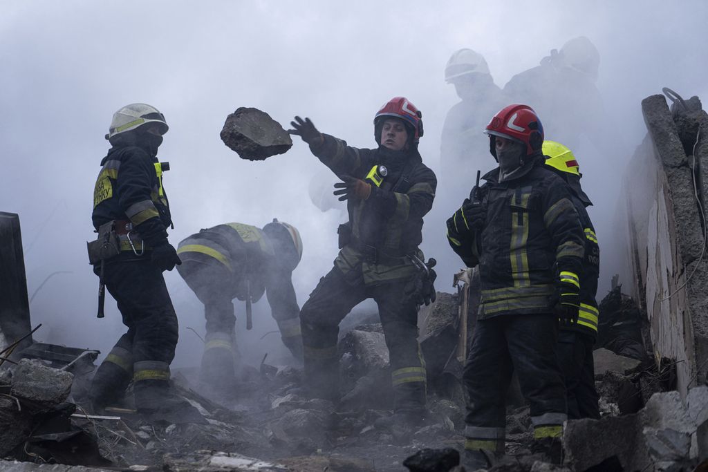 Para pekerja meindahkan puing-puing reruntuhan bangunan sebuah gedung apartemen yang hancur akibat gempuran roket Rusia di area permukiman di Dnipro, Ukraina tenggara, 15 Januari 2023. 