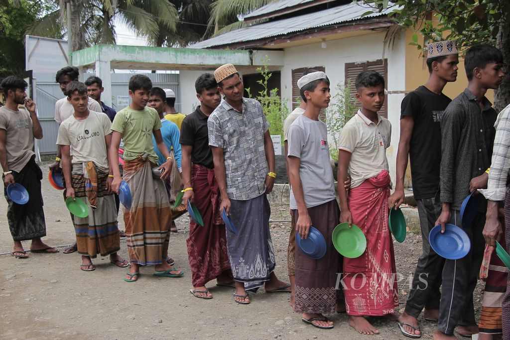 Pengungsi etnis Rohingya antre makan siang di tempat penampungan sementara di Yayasan Mina, Kecamatan Padang Tiji, Kabupaten Pidie, Aceh, Jumat (23/11/2023). 