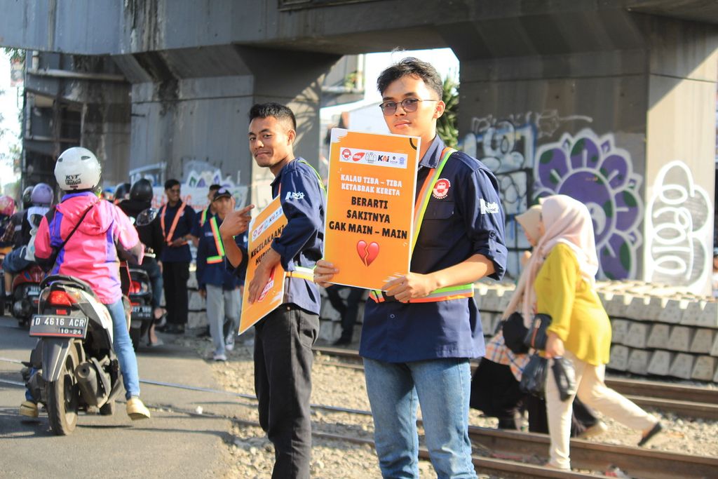 Sejumlah anggota Komunitas Edan Sepur Indonesia memberikan sosialisasi bagi warga di dekat area pelintasan kereta api di Stasiun Cimindi, Kota Bandung, Jawa Barat, 15 Desember 2023. Komunitas pencinta kereta ini melaksanakan sosialisasi agar warga berhati-hati saat melewati pelintasan kereta api.