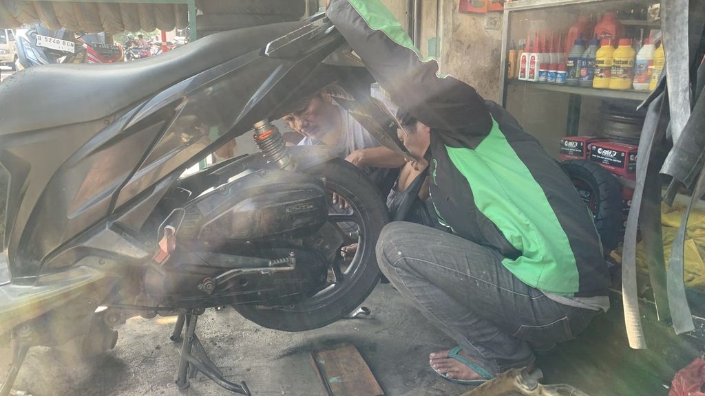Abdul Majid, pemudi ojek daring, harus mengganti ban motornya karena bocor cukup parah saat berkendara di Jalan Daan Mogot, Kebon Jeruk, Jakarta Barat, Selasa (7/3/2023).