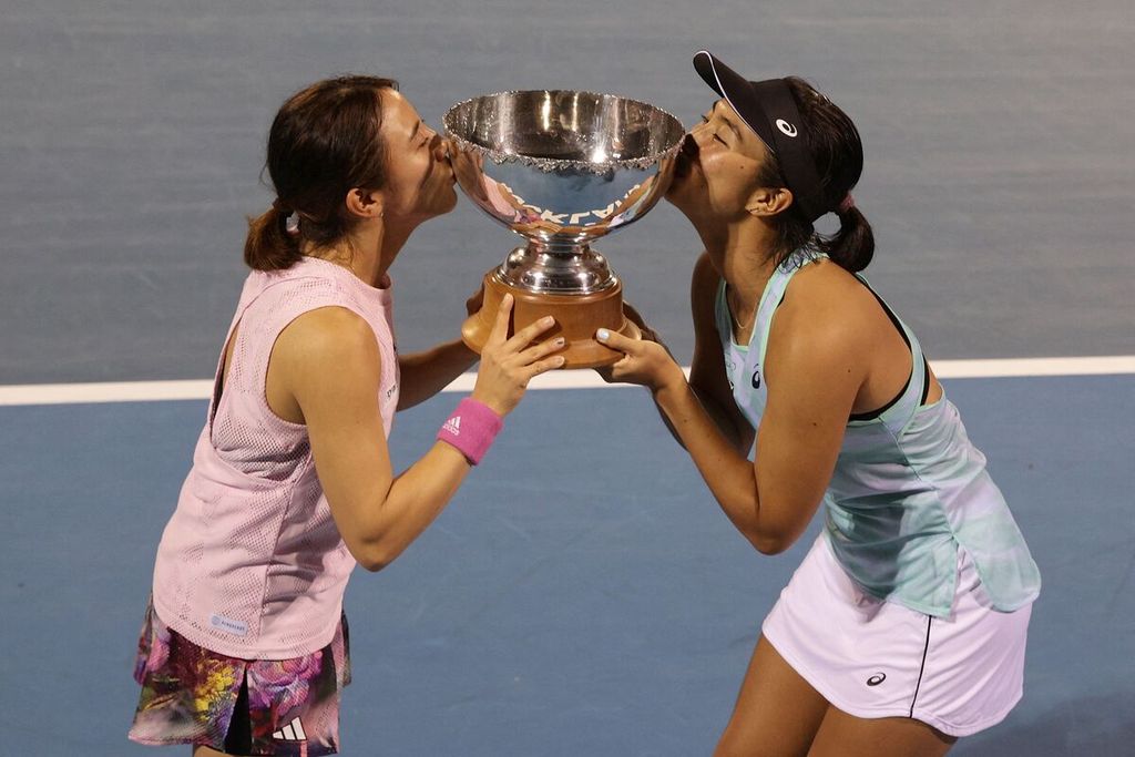 Petenis putri Indonesia, Aldila Sutjiadi (kanan), dan pasangannya asal Jepang, Miyu Kato, mencium trofi juara WTA Auckland setelah mengalahkan Leylah Fernandez/Bethanie Mattek-Sands di Auckland, Selandia Baru, 9 Januari 2023.