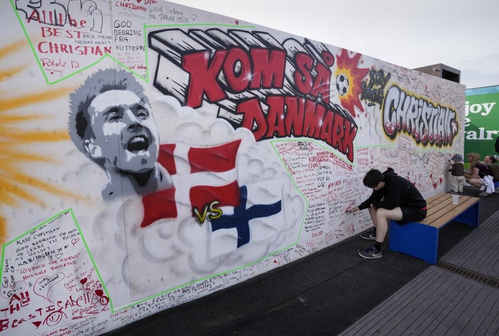 Warga menulis harapan mereka bagi kesembuhan pemain timnas Denmark, Christian Eriksen, dalam sebuah tulisan di tembok, di Copenhagen, Denmark, Senin (14/6/2021). Eriksen dirawat di rumah sakit setelah mengalami serangan jantung ketika timnya melawan Finlandia pada Piala Eropa, Sabtu (12/6/2021).