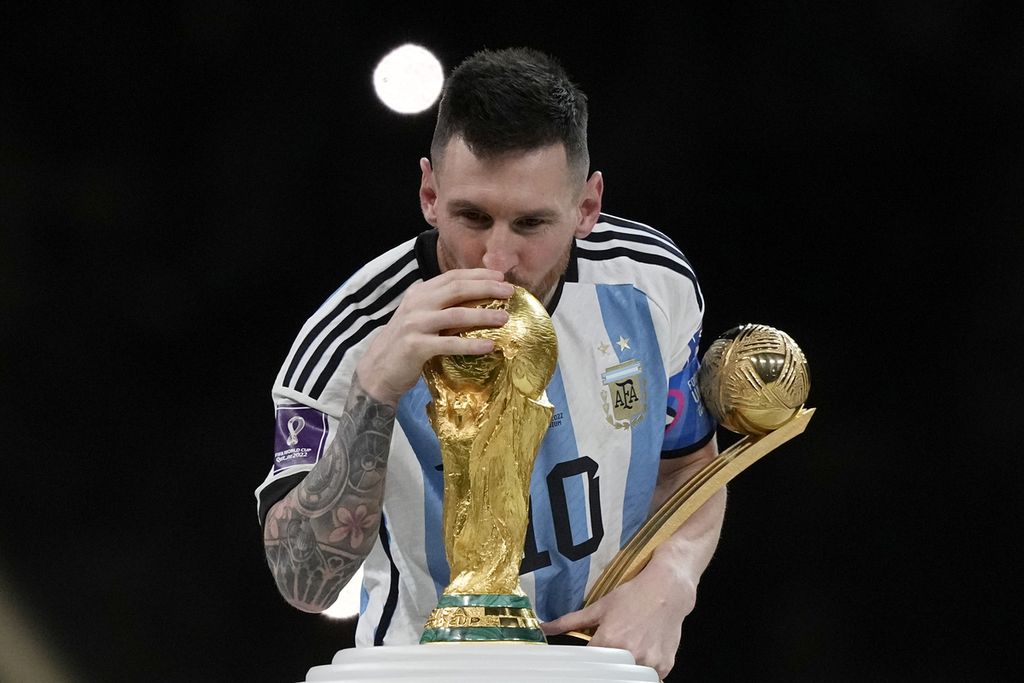 Lionel Messi, pemain sepak bola Argentina, mencium trofi setelah memenangi pertandingan sepak bola final Piala Dunia antara Argentina dan Perancis di Stadion Lusail, Lusail, Qatar, Minggu (18/12/2022). Argentina menang 4-2 dalam adu penalti setelah pertandingan berakhir imbang 3 -3. 