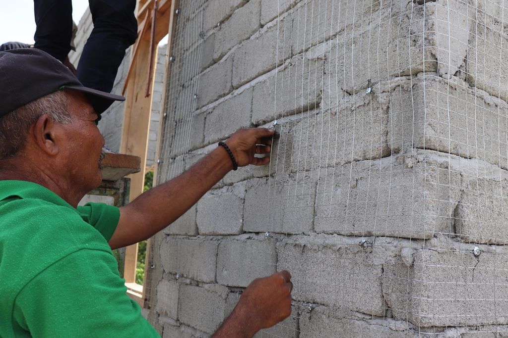 Seorang tukang memasang kawat pada dinding sebuah rumah untuk menghasilkan rumah aman gempa dalam pelatihan di Desa Rogo, Kecamatan Dolo Selatan, Kabupaten Sigi, Sulteng, Senin (2/12/2019). 