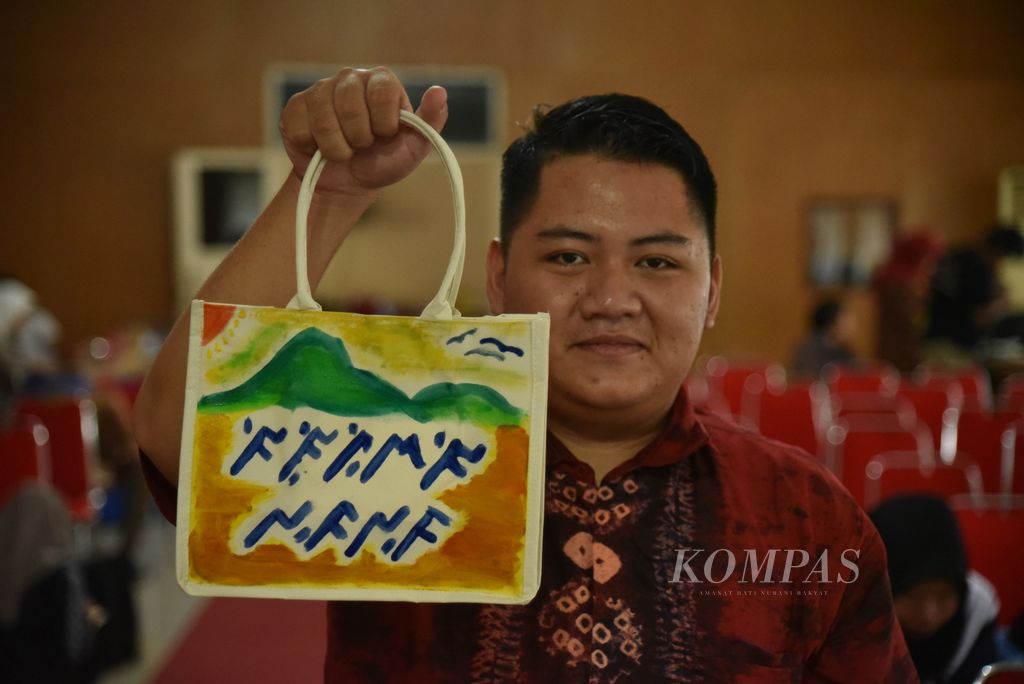 Peserta dari Universitas Sriwijaya, Eugene Lakilaki, menunjukkan hasil karyanya seusai mengikuti <i>workshop</i> ”Merawat Aksara Ulu Sumatera Selatan” di Perpustakaan Daerah Sumsel, Palembang, Selasa (31/10/2023). 