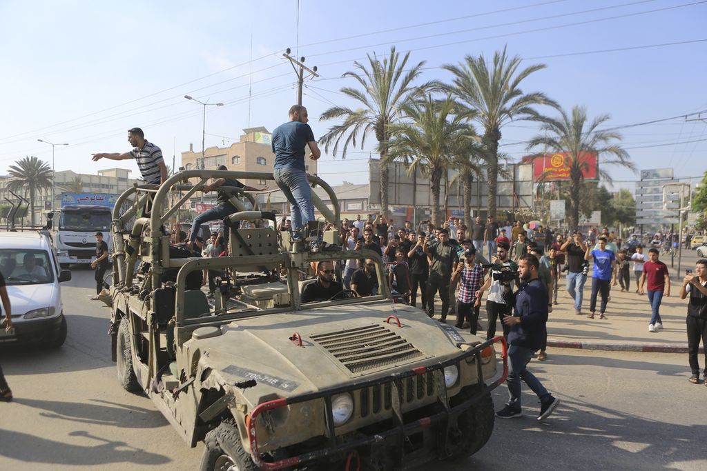 Warga Palestina menaiki kendaraan militer Israel di pangkalan militer Israel yang berhasil direbut oleh Hamas di Gaza pada 7 Oktober 2023.