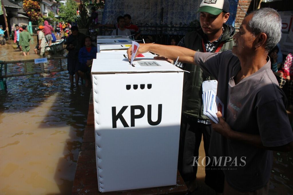 Pemilih memasukkan surat suara ke dalam kotak suara di TPS 18 Dayeuhkolot, Kabupaten Bandung, Jawa Barat, Rabu (17/4/2019). Hujan lebat pada Selasa malam membuat sejumlah TPS di Dayeuhkolot tergenang banjir.