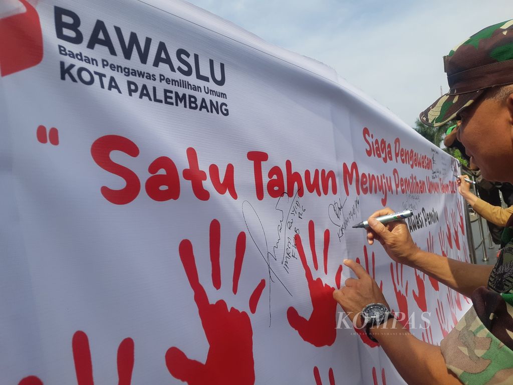 Seorang anggota TNI menandatangani spanduk Siaga Pengawasan Satu Tahun Menuju Pemilihan Umum 2024 di pelataran Benteng Kuto Besak, Palembang, Sumatera Selatan, Selasa (14/2/2023). 