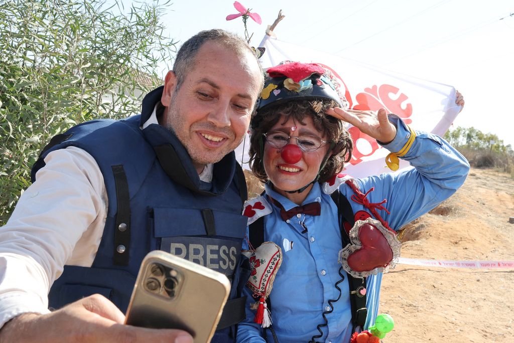 Seorang aktivis perdamaian Israel, berpakaian seperti badut, berfoto dengan seorang wartawan, saat berkumpul di Sderot dekat perbatasan dengan Jalur Gaza, untuk menyatakan dukungan terhadap para sandera yang ditahan Hamas Palestina pada 10 November 2023. 