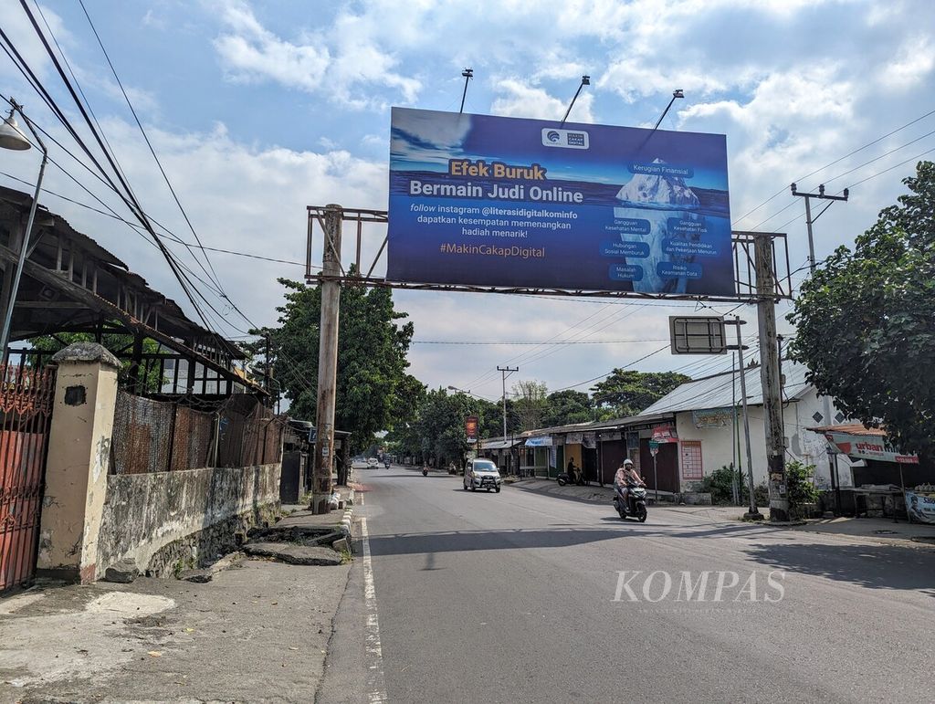 Pengguna jalan melintas di bawah baliho besar berisi imbauan tentang efek buruk bermain judi <i>online </i>atau judi daring di kawasan Jalan Sriwijaya, Kota Mataram, Nusa Tenggara Barat, Senin (17/6/2024).