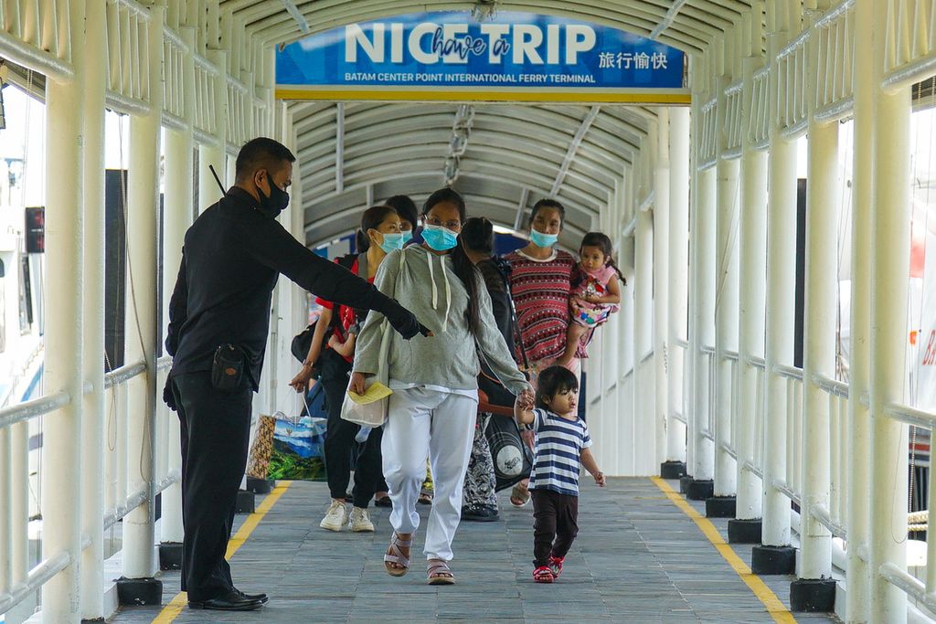 Petugas keamanan mengatur pekerja migran Indonesia agar menjaga jarak seusai dengan protokol penanganan Covid-19 saat mereka tiba di Pelabuhan Internasional Batam Centre, Kota Batam, Kepulauan Riau, Kamis (21/5/2020).
