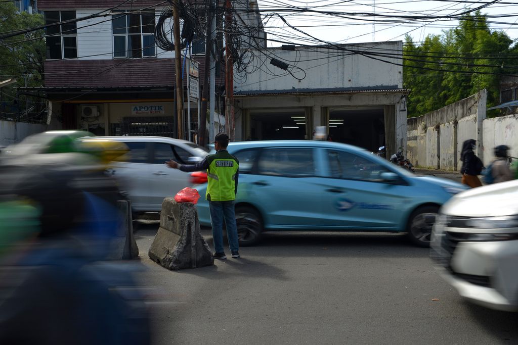 Seorang pengatur lalu lintas liar mengatur kendaraan yang melintas di Jalan Palmerah Utara, Jakarta Barat, Jumat (10/2/2023).