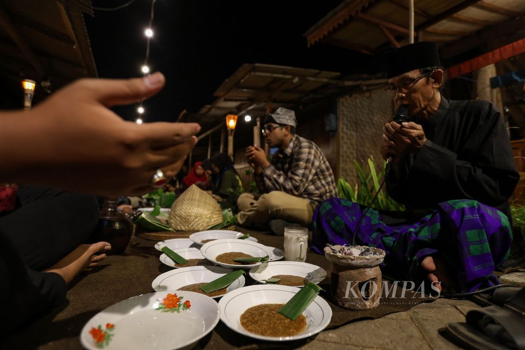 Ketua Lembaga Adat Kemiren Suhaimi memimpin doa dalam acara selamatan di Desa Kemiren, Kabupaten Banyuwangi, Jawa Timur, untuk makan bersama pada Jumat (17/11/2023). Setelah didoakan, makanan yang disajikan baru boleh dimakan. 