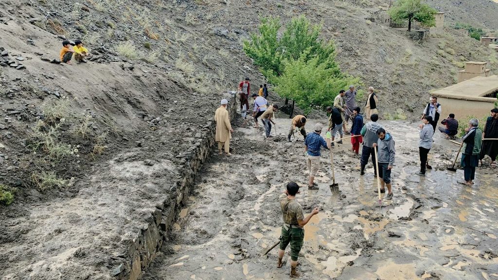 Warga membersihkan jalanan di Desa Dara, Provinsi Panjshir, Afghanistan, yang tertutup lumpur setelah diterjang banjir bandang, Senin (15/7/2024). Warga Afghanistan menyekop lumpur setelah wilayah itu dilanda banjir bandang. Laporan langsung dari lokasi kejadian penting dilakukan oleh media.