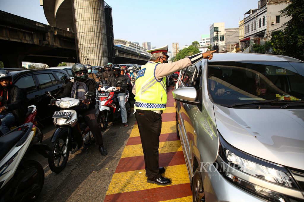 Petugas mengingatkan pengemudi kendaraan saat akan memasuki kawasan penerapan ganjil genap di Jalan Fatmawati, Jakarta Selatan, Senin (25/10/2021). 