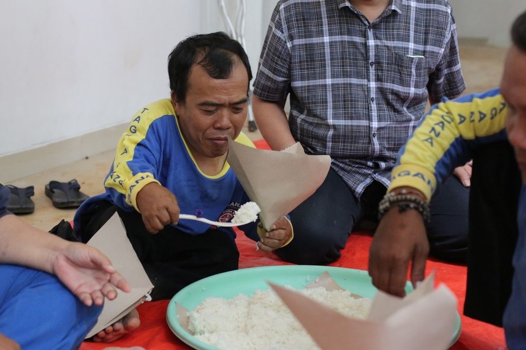 Alip Budiarto, Tagana Disabilitas dari Semarang, Jawa Tengah, sedang membungkus nasi di posko pengungsian untuk dibagikan kepada para korban bencana.