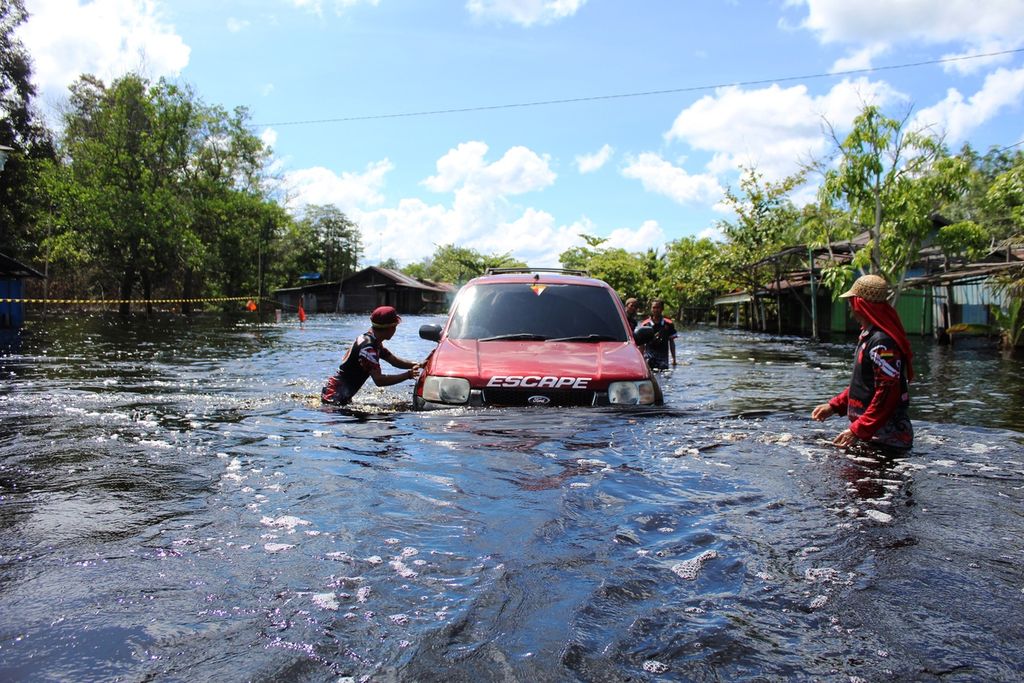 Sukarelawan membantu mobil-mobil yang kesulitan maju di tengah banjir dengan cara mendorongnya, Minggu (21/11/2021), Di Kalteng, banjir tak kunjung surut seiring tingginya intensitas hujan.