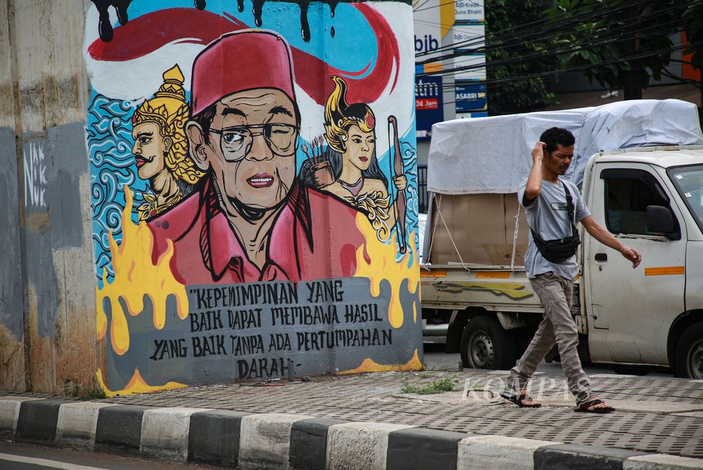 Warga melintas di dekat mural bergambar wajah Presiden Indonesia Ke-4 RI KH Abdurrahman Wahid atau dikenal dengan Gus Dur di dekat Pasar Cipulir, Jakarta Selatan, Jumat (9/9/2022). 