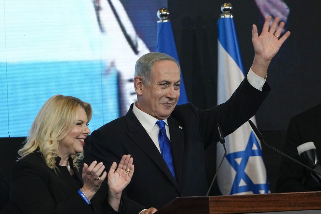 Benjamin Netanyahu, pemimpin Partai Likud, didampingi istrinya, Sara, melambaikan tangan ke para pendukungnya di markas pemenangan partai di Jerusalem, Selasa (2/11/2022). 
