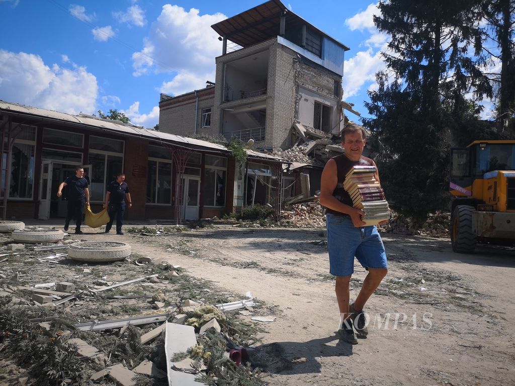 Para pegawai sekolah dibantu petugas penyelamat mengeluarkan buku-buku dan sejumlah barang dari dalam sekolah yang hancur dihantam rudal Rusia, di Distrik Shevchenkivskiy Kharkiv, Ukraina, Senin (4/7/2022). Sekolah ini dibom pada Senin pukul 04.00 waktu setempat.