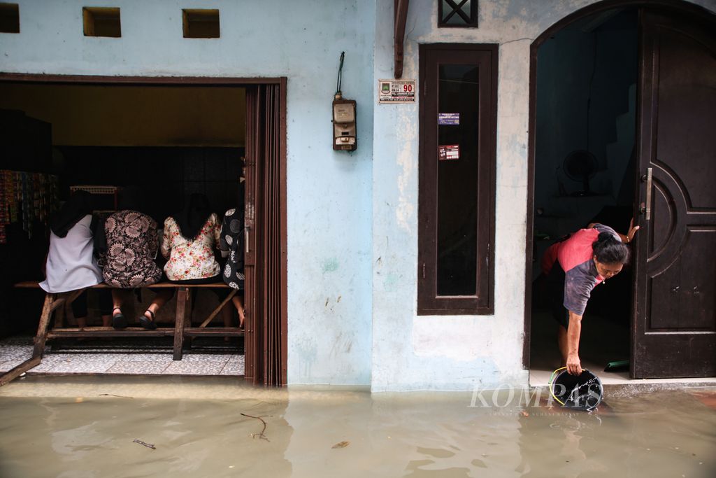 Seorang warga memanfaatkan air banjir untuk membersihkan rumahnya setelah banjir mulai surut di kelurahan Larangan Utara, Larangan, Kota Tangerang, Banten, Jumat (24/2/2023).