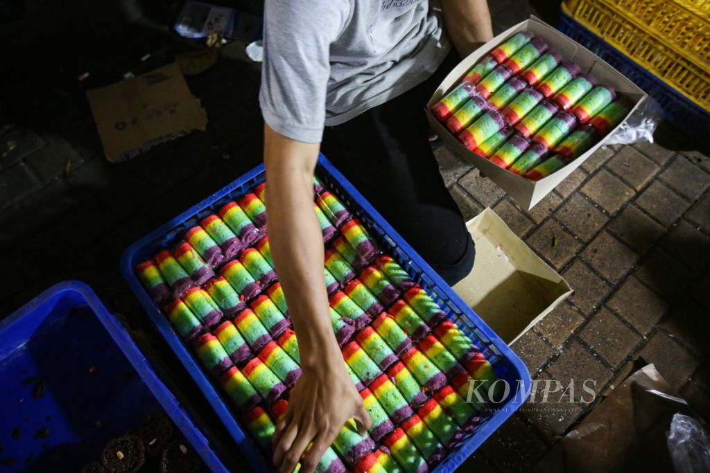 Pedagang mempersiapkan bolu pelangi pesanan pelanggan di Pasar Kue Subuh Blok M, Jakarta Selatan, Rabu (10/01/2024). Kue-kue di pasar tersebut dijual secara grosir dan eceran. Bolu Pelangi dijual Rp 1.500 per potong. 